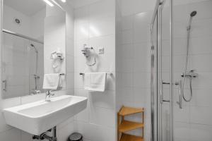 uma casa de banho branca com um lavatório e um chuveiro em 7Days B&B em Bratislava