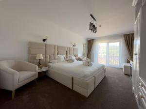 1 dormitorio blanco con 1 cama grande y 1 silla en Regatul Bucovinei, en Suceava