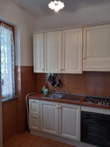 a kitchen with white cabinets and a sink at Roma a un passo e il mare in casa in Marina di Cerveteri