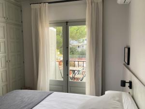 1 dormitorio con 1 cama y puerta corredera de cristal en Calendula Hotel, en Sant Feliu de Guíxols