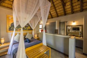 Lindiwe Safari Lodge في هويدزبروت: غرفة نوم بسرير مع ناموسية