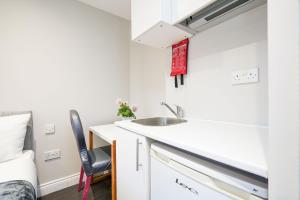 a small kitchen with a sink and a bed at Cosy studio flat (Finchley Rd) in London