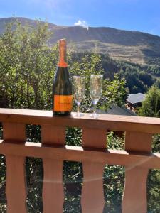 una botella de vino sentada en un banco con copas de vino en Chalet Le Lauzet en Les Deux Alpes