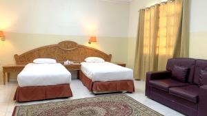 een hotelkamer met 2 bedden en een stoel bij Super OYO 151 Manam 2 Hotel Apartment in Muscat