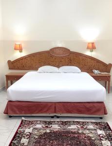 een slaapkamer met een groot bed met een houten hoofdeinde bij Super OYO 151 Manam 2 Hotel Apartment in Muscat