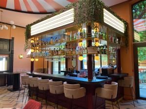 a bar in a restaurant with white stools at ClapClap Hôtel Strasbourg in Strasbourg