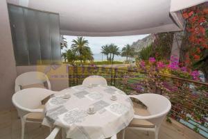 - une table et des chaises blanches sur un balcon fleuri dans l'établissement Apar2amento maravillo2o Con vistas al mar, à Calp