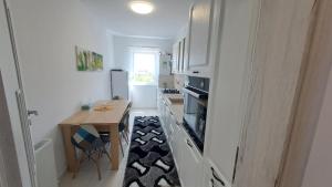a kitchen with white cabinets and a table and a dining room at Apartament Ramonte in Zărneşti