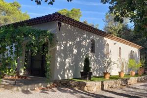 un pequeño edificio blanco con un arco y vides en Charmante Villa Ipsilon, jardin arboré provençal !, en Le Luc