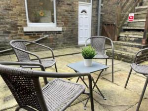 three chairs and a table with a potted plant on a patio at 3 Bedroom House Brighouse in Brighouse