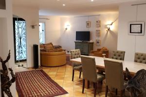 sala de estar con mesa, sillas y TV en Charmante Villa Ipsilon, jardin arboré provençal !, en Le Luc
