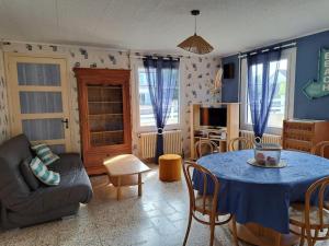 een woonkamer met een blauwe tafel en stoelen bij Gîte Le Scoubidou, bord de mer in Saint-Jean-le-Thomas