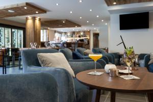 レ・ジェにあるAnnapurna by Alpine Residencesの青いソファとワイングラス付きのテーブルが備わるレストラン