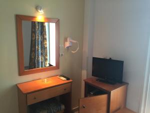 a room with a television and a mirror and a dresser at Iris Hotel in Nea Kallikrateia