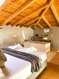 a large bed in a room with wooden ceilings at Modern Stone Villas with Swimming Pool in Aliveri