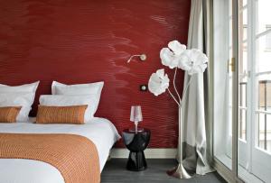 a bedroom with a red wall with a bed and white flowers at Hôtel Rohan Strasbourg in Strasbourg +57 photos