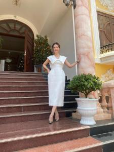 Una mujer con un vestido blanco parada en unas escaleras en Minh Cường Hotel, en Mộc Châu