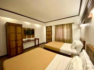 a hotel room with two beds and a television at El Puerto Marina Beach Resort & Vacation Club in Lingayen