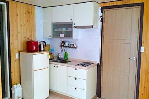 una piccola cucina con armadietti bianchi e una porta di Haeoreum Pension a Ullŭng