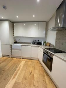 a kitchen with white cabinets and a wooden floor at Notting Hill Studio Room in London