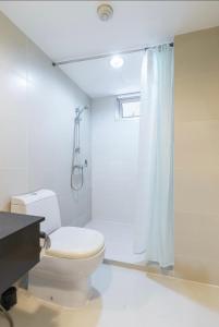y baño blanco con aseo y ducha. en Belle Rama9 精品公寓 en Bangkok