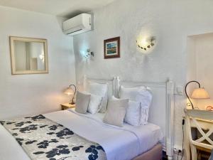 een slaapkamer met een wit bed met witte kussens bij Hôtel Porte de Camargue - Les Quais d'Arles in Arles
