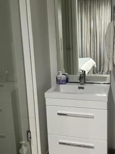 W białej łazience znajduje się umywalka i lustro. w obiekcie Pebble Beach Sibaya No.122 w mieście Sibaya