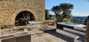 um pátio com uma banheira de hidromassagem, uma mesa e cadeiras em Provencal stone farmhouse with sea view, swimming pool and spa em Tourrettes-sur-Loup