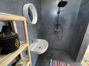 y baño con lavabo y ducha con espejo. en La Maison de Mohamed en Wassane