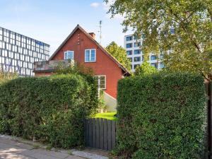 ein rotes Haus hinter einigen Büschen vor Gebäuden in der Unterkunft Sanders Charm - Cozy One-Bedroom Apartment with Shared Garden in Kopenhagen