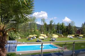 einen Pool mit Stühlen und Sonnenschirmen in einem Resort in der Unterkunft Dei Hotel Schönblick in Velden am Wörthersee