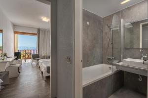 a bathroom with a tub and a sink and a shower at Skiathos Palace Hotel in Koukounaries