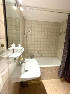 ein Badezimmer mit einem Waschbecken und einer Badewanne in der Unterkunft Augsburg Hotelturm in Augsburg
