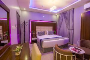 een paarse slaapkamer met een bed en een bank bij Swat Hotel Apartments in Dammam