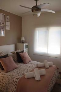 um quarto com 2 camas com almofadas e uma ventoinha em Precioso apartamento con vistas al mar. Piscina. em Valência