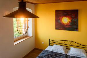 Schlafzimmer mit einem Bett, einem Fenster und einem Kronleuchter in der Unterkunft LAAS ART GALLERY in Stari Trg pri Ložu