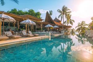 una piscina en un resort con sillas y sombrillas en Bali Mandira Beach Resort & Spa, en Legian
