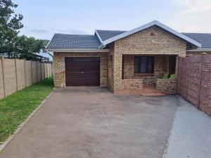 a brick house with a garage and a fence at M&M Self Catering in Richards Bay