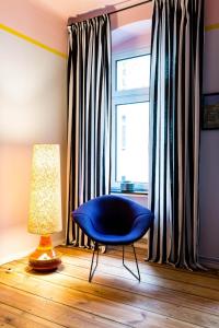 a blue chair sitting in front of a window at One Bedroom Apartment with Balcony H12 in Berlin