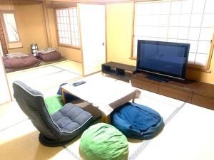 ein Wohnzimmer mit einem TV, einem Stuhl und einem Tisch in der Unterkunft Tokyo KD House 301 in Tokio