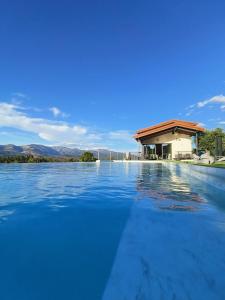 una piscina d'acqua con una casa sullo sfondo di Casa rural Atalanta de la Vera a Jaraiz de la Vera