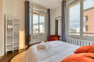 ein Schlafzimmer mit zwei Handtüchern auf einem Bett mit Fenstern in der Unterkunft Cosy Jungle Un magnifique F5 in Rouen
