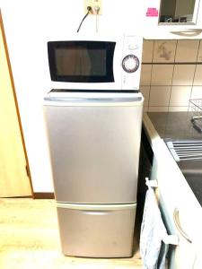 eine Mikrowelle auf einem Kühlschrank in der Küche in der Unterkunft Tokyo KD House 301 in Tokio