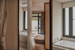 Un baño con bañera, cama y espejo. en Creek Moganshan Design B&B, en Deqing 43 fotos más