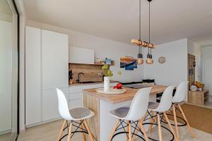 una cocina con armarios blancos y taburetes blancos en Sunset Apartments, en Blato