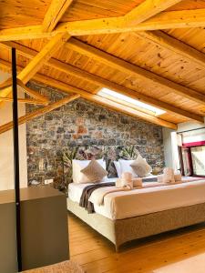 Cama grande en habitación con pared de piedra en Modern Stone Villas with Swimming Pool en Aliveri