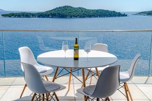 una mesa y sillas blancas con una botella y copas de vino en Sunset Apartments, en Blato