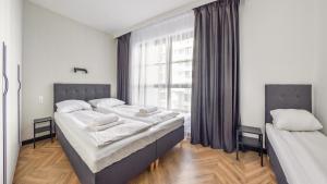 a bedroom with two beds and a large window at Apartamenty Sun & Snow Doki in Gdańsk