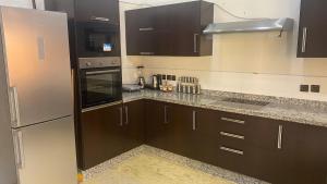 La cuisine est équipée de placards bruns et d'un réfrigérateur en acier inoxydable. dans l'établissement Villa Targa, à Marrakech