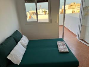 divano verde in camera con finestra di STUDIO MIRAMAR MARTIL ll a Martil